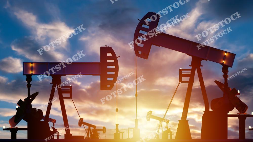 На изображении показаны силуэты нескольких нефтяных качалок, работающих на фоне закатного неба. Свет солнца усиливает драматичность и подчёркивает значение индустрии. Фотография иллюстрирует ключевую роль нефти в мировой энергетике.